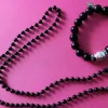 Tradera Halsband<Svart halsband och armband. Armbandet har en figur och bredvid den stenar.